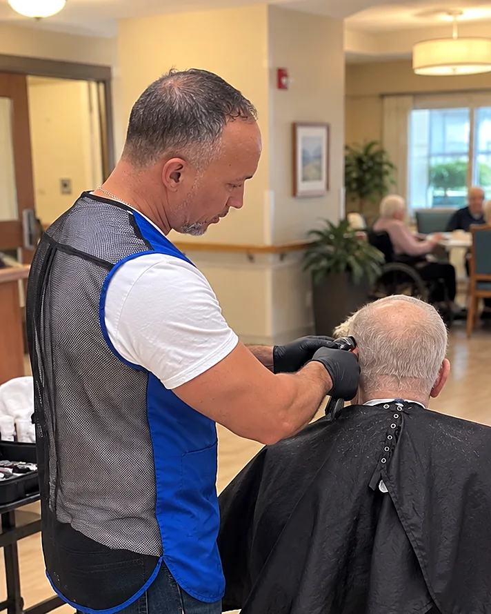 Hair & Cuts barber giving a resident in a wheelchair a haircut at a senior living community in NYC