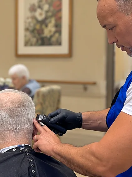 Careful clipper haircut for a senior resident by a Hair & Cuts barber